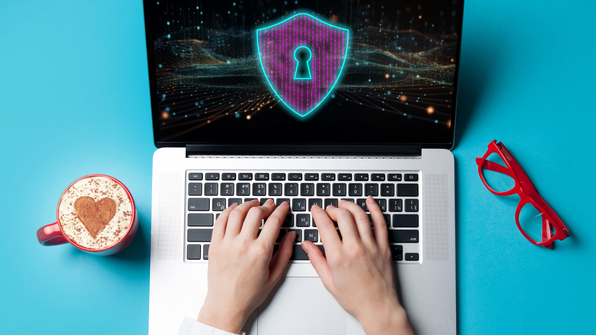 Persona con un café y gafas trabajando en un portátil con un escudo digital en pantalla que representa la protección de datos y la ciberseguridad de INTK