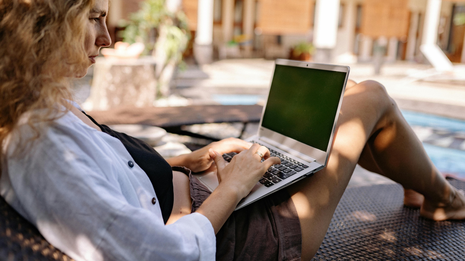 Persona utilizando un ordenador port&aacute;til en un espacio exterior, imagen asociada al teletrabajo, la conectividad y la seguridad digital
